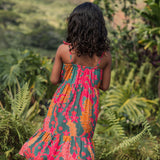 girl with brown hair wearing a colorful dress with tropical lei print