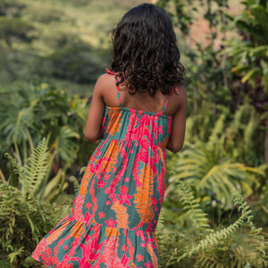 girl with brown hair wearing a colorful dress with tropical lei print