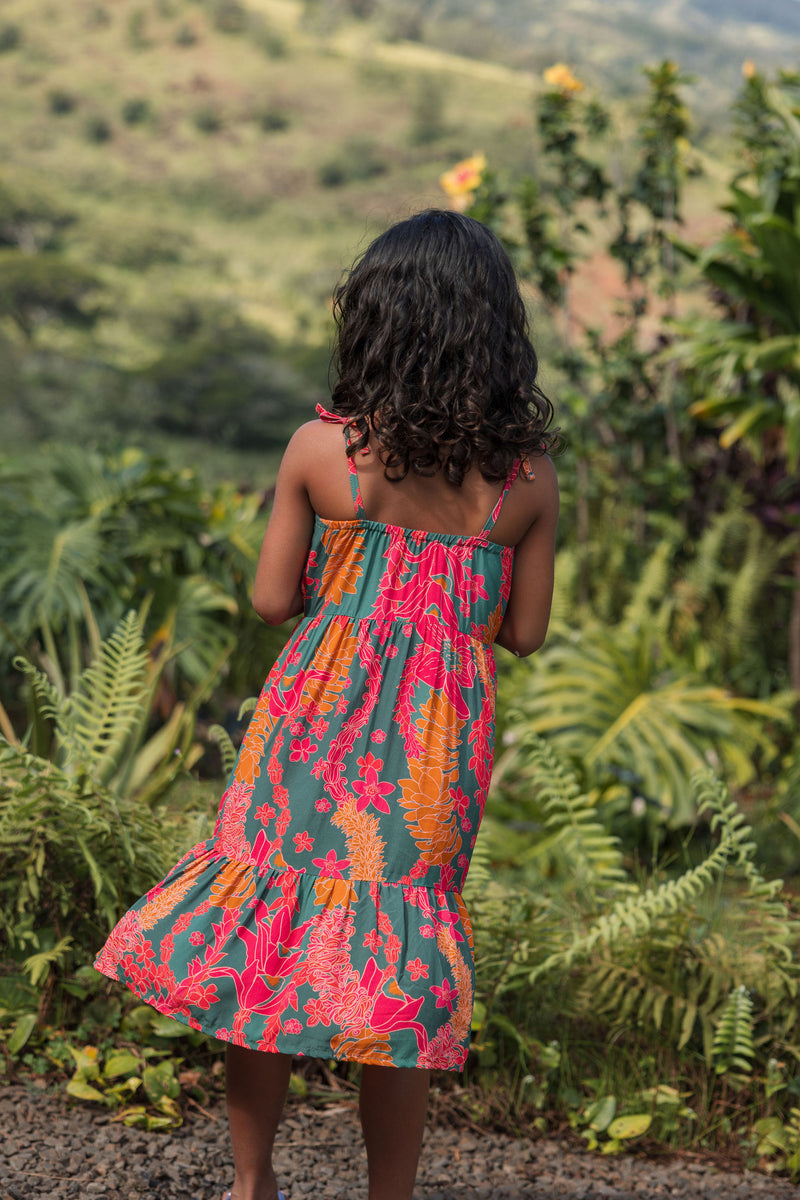 girl with brown hair wearing a colorful dress with tropical lei print