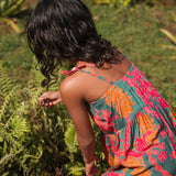 girl with brown hair wearing a colorful dress with tropical lei print