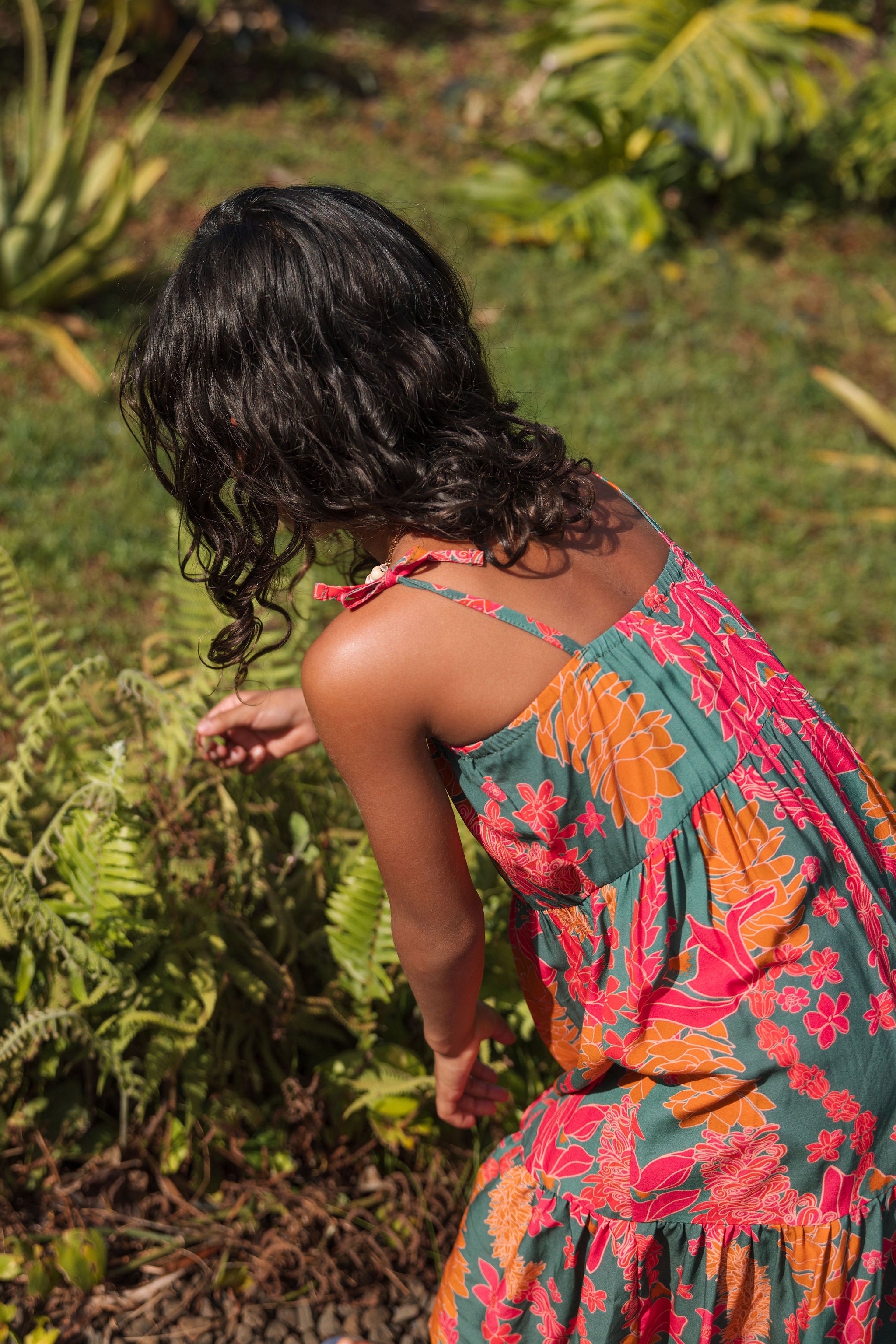 girl with brown hair wearing a colorful dress with tropical lei print