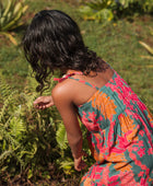 girl with brown hair wearing a colorful dress with tropical lei print