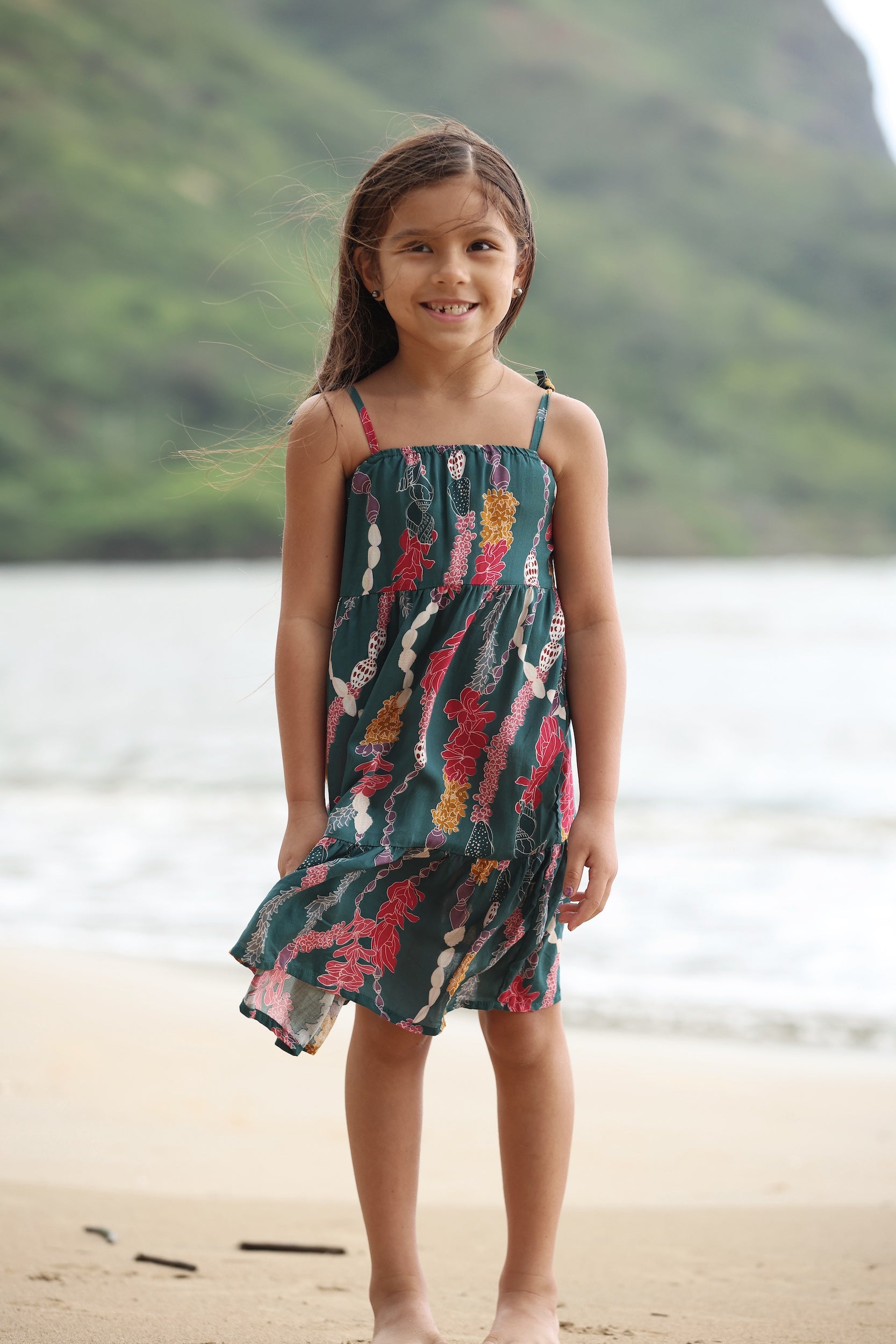 little girl wearing a knee length dress with tie spaghetti straps in dark teal with shell and lei print