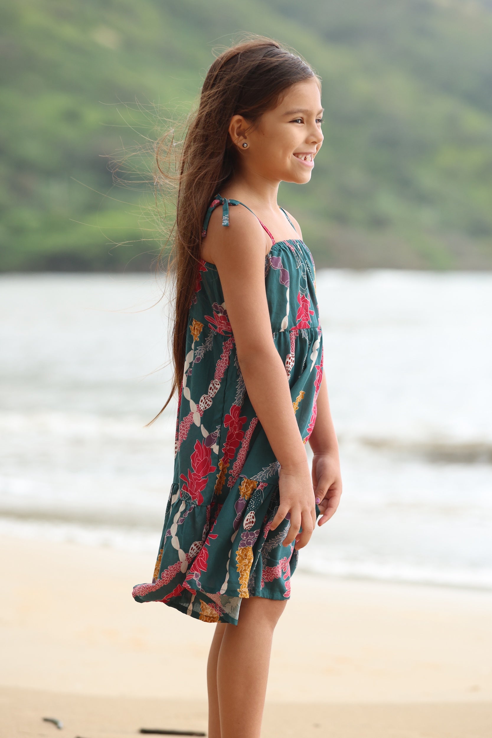 little girl wearing a knee length dress with tie spaghetti straps in dark teal with shell and lei print