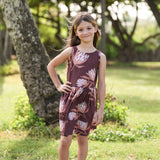 little girl wearing brown high neck, sleeveless dress with protea print