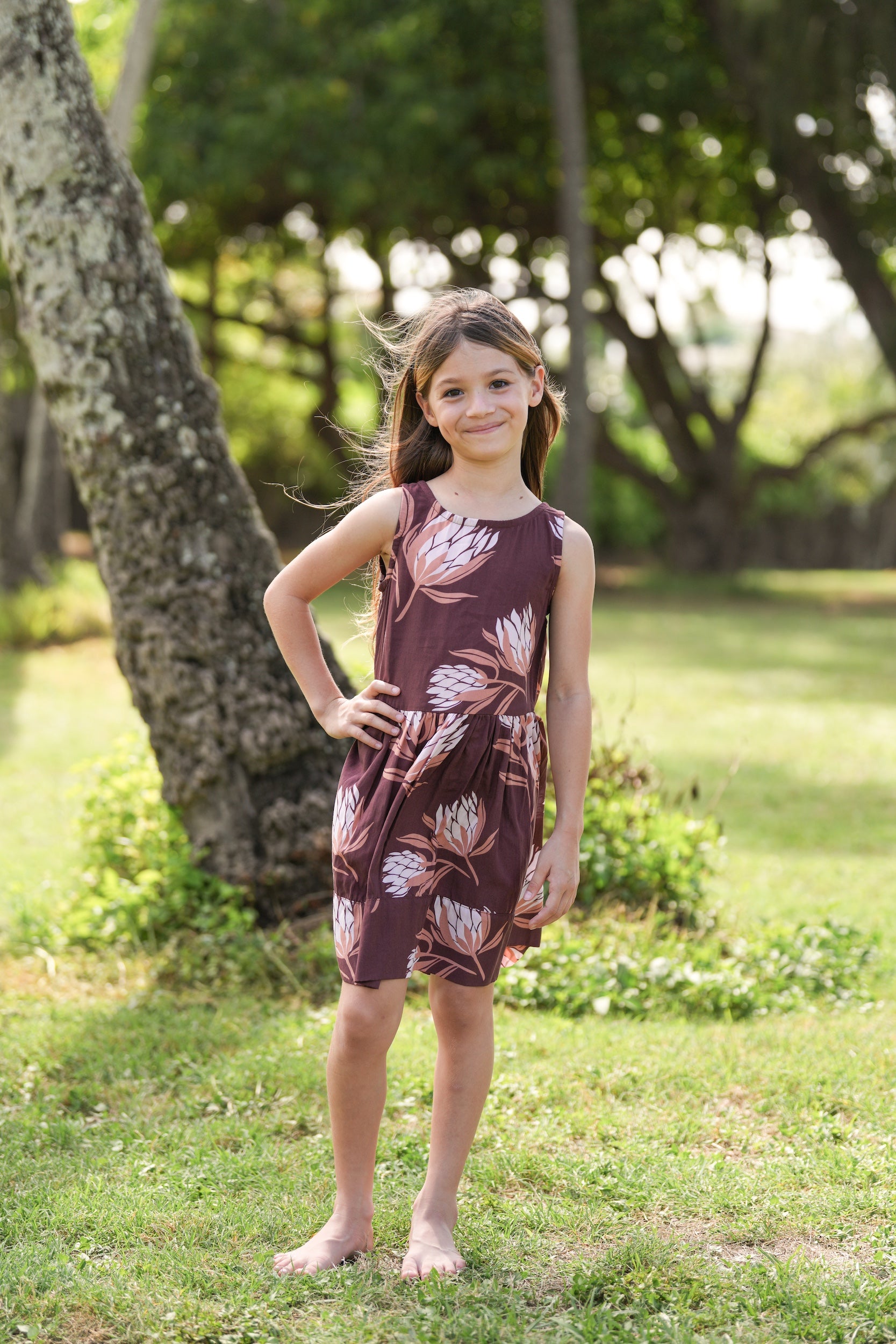 little girl wearing brown high neck, sleeveless dress with protea print