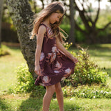 little girl wearing brown high neck, sleeveless dress with protea print