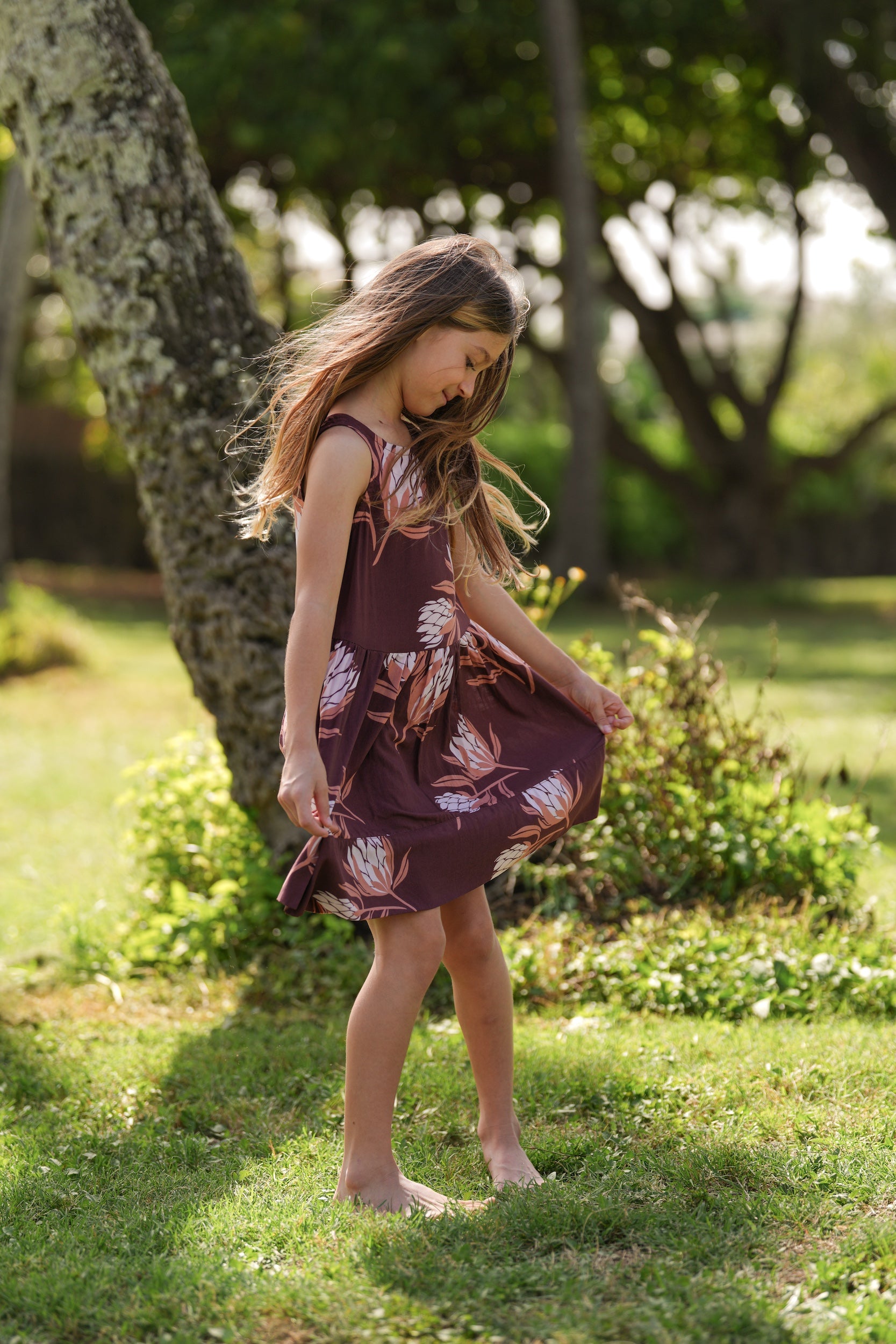 little girl wearing brown high neck, sleeveless dress with protea print