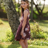 little girl wearing brown high neck, sleeveless dress with protea print