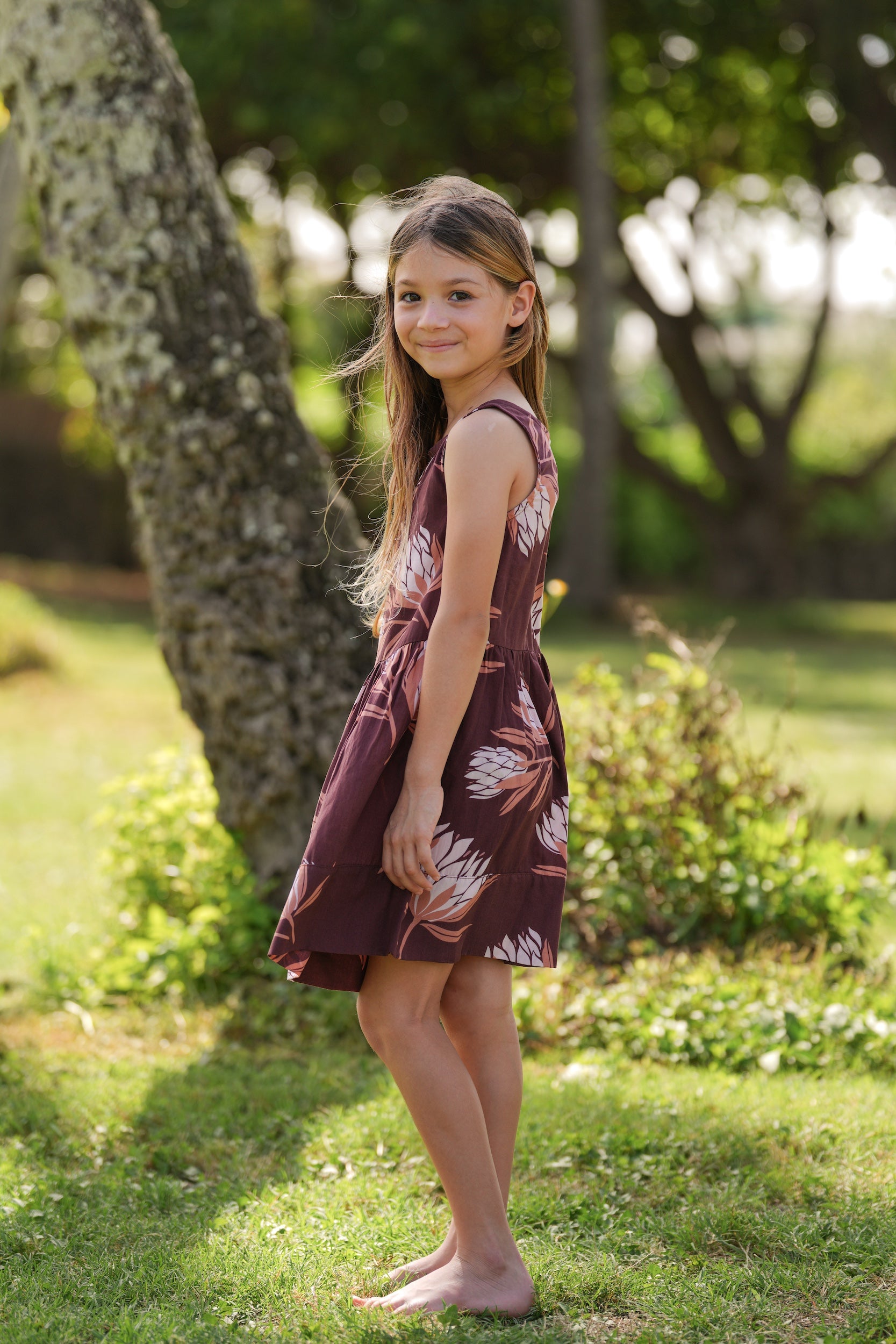 little girl wearing brown high neck, sleeveless dress with protea print