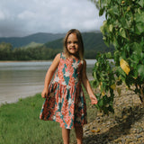 little girl wearing a knee length dress with red ginger and tiare print