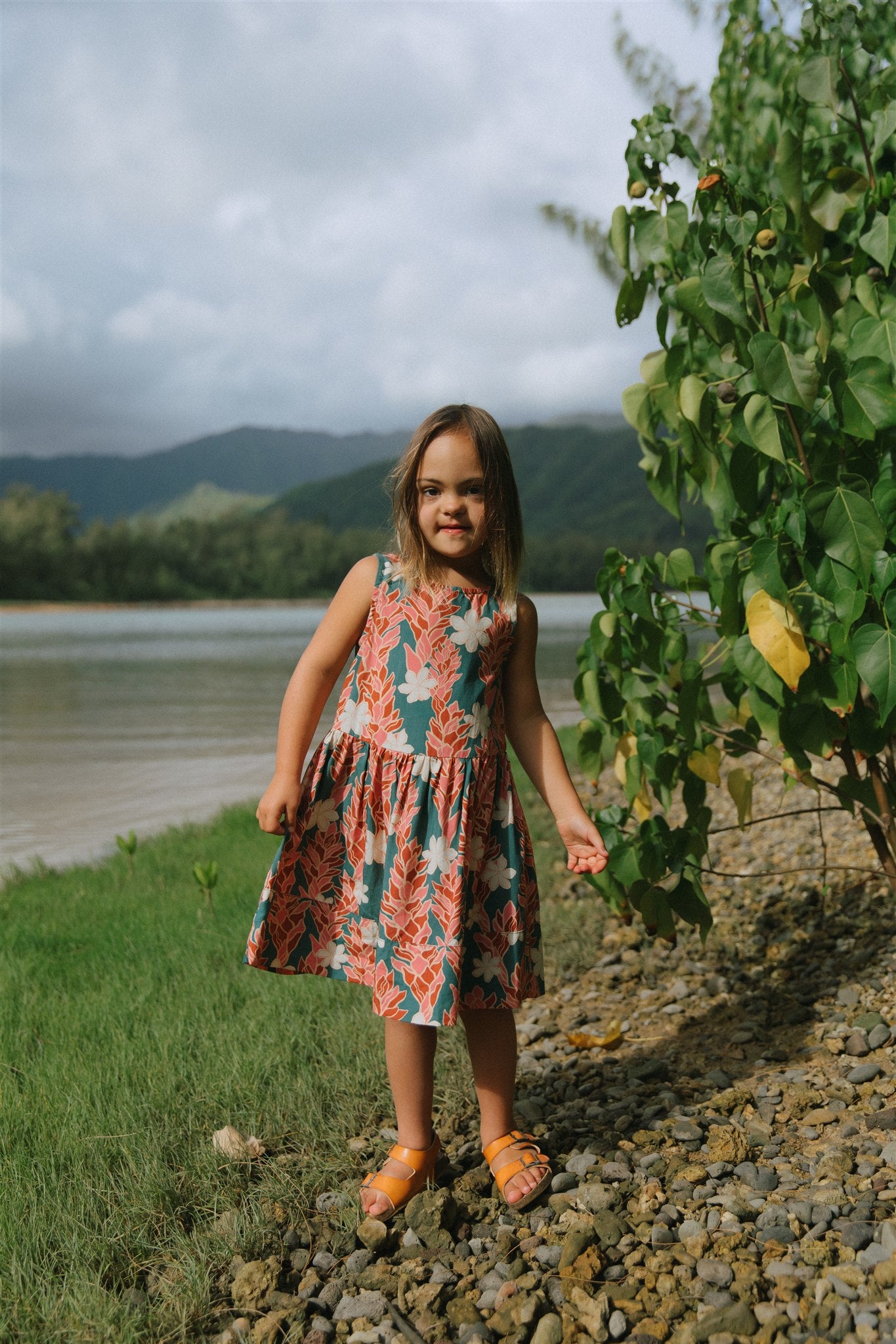 little girl wearing a knee length dress with red ginger and tiare print