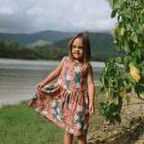 little girl wearing a knee length dress with red ginger and tiare print