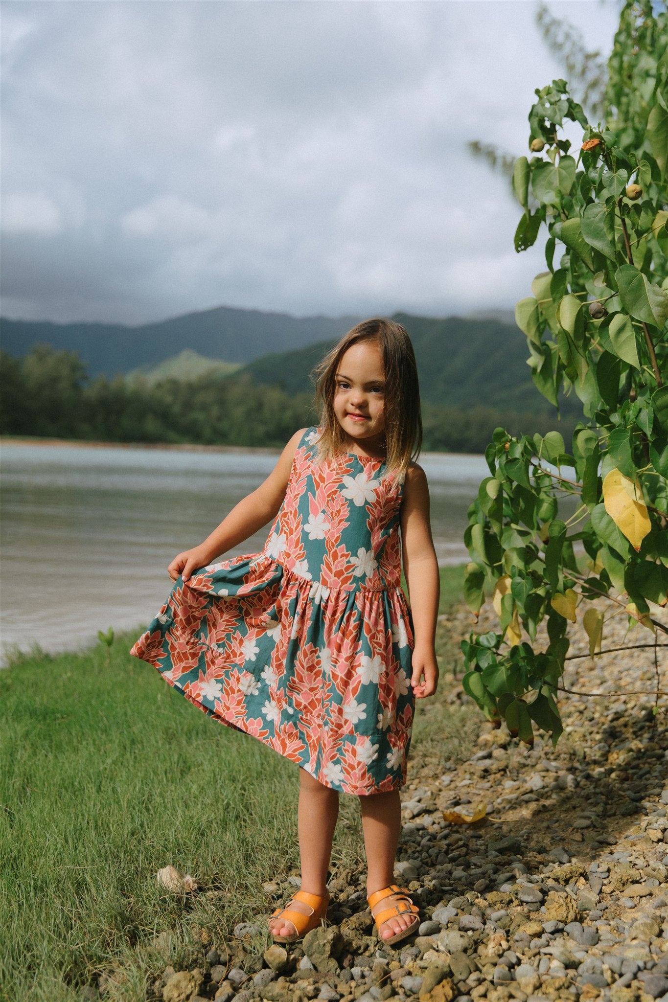 little girl wearing a knee length dress with red ginger and tiare print
