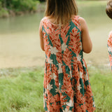 little girl wearing a knee length dress with red ginger and tiare print
