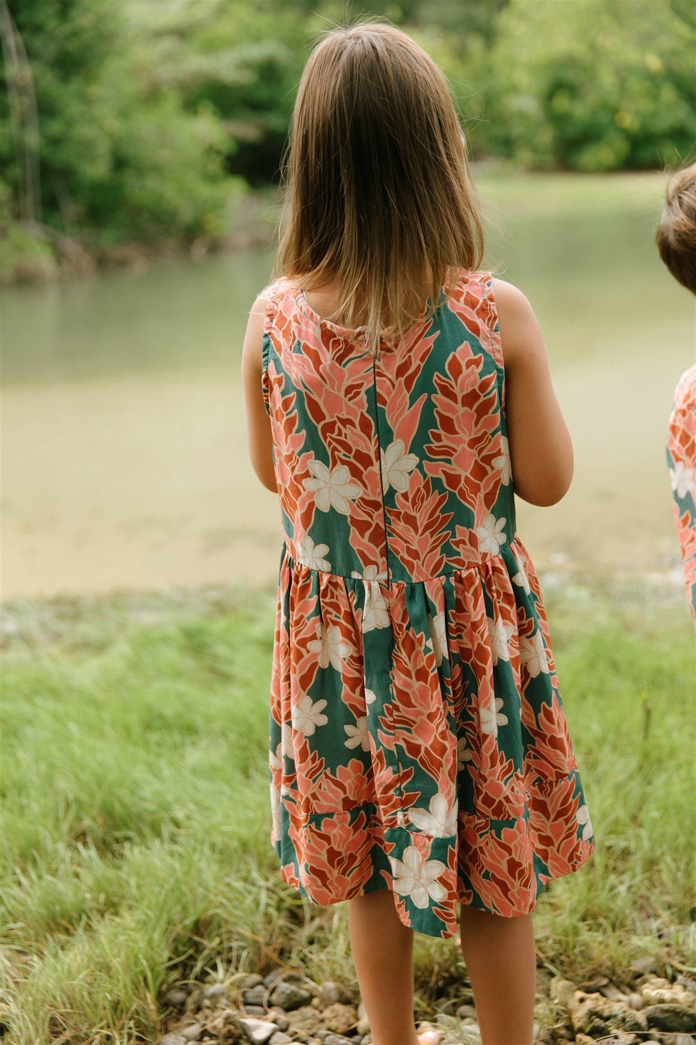 little girl wearing a knee length dress with red ginger and tiare print