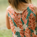 little girl wearing a knee length dress with red ginger and tiare print