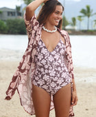 Woman with brown hair wearing a one piece v-neck bikini in blush and brown hibiscus print.