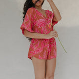 woman with brown hair wearing a sienna colored playsuit with mid length sleeves and awapuhi pattern