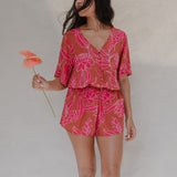 woman with brown hair wearing a sienna colored playsuit with mid length sleeves and awapuhi pattern