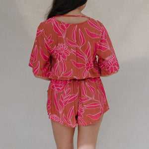 woman with brown hair wearing a sienna colored playsuit with mid length sleeves and awapuhi pattern