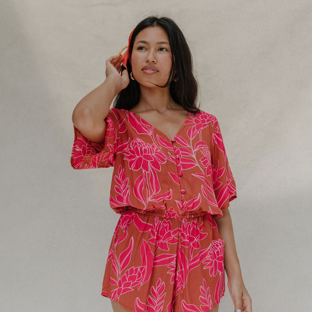 woman with brown hair wearing a sienna colored playsuit with mid length sleeves and awapuhi pattern