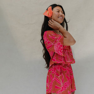 woman with brown hair wearing a sienna colored playsuit with mid length sleeves and awapuhi pattern