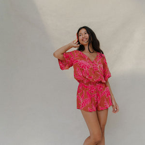 woman with brown hair wearing a sienna colored playsuit with mid length sleeves and awapuhi pattern