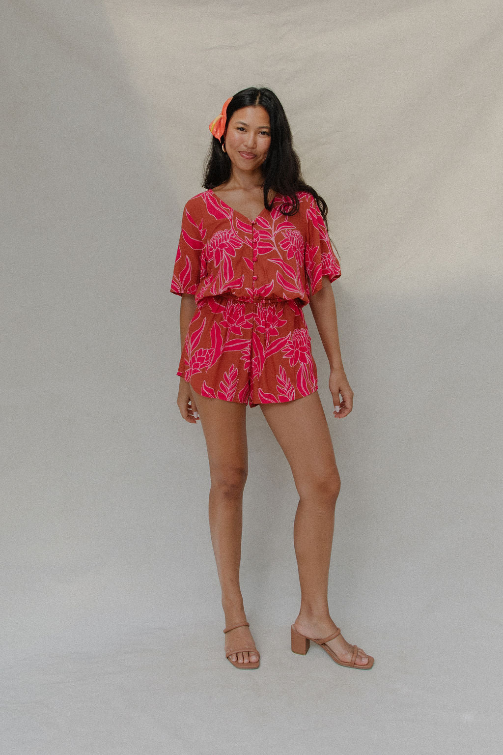 woman with brown hair wearing a sienna colored playsuit with mid length sleeves and awapuhi pattern