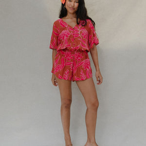 woman with brown hair wearing a sienna colored playsuit with mid length sleeves and awapuhi pattern