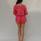 woman with brown hair wearing a sienna colored playsuit with mid length sleeves and awapuhi pattern