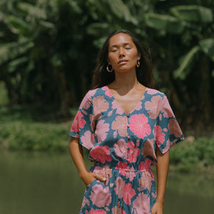 woman with brown hair wearing a navy playsuit with bright pink hibiscus print