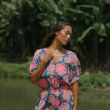 woman with brown hair wearing a navy playsuit with bright pink hibiscus print