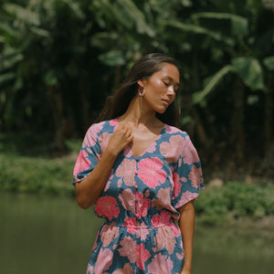 woman with brown hair wearing a navy playsuit with bright pink hibiscus print