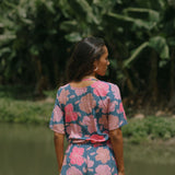 woman with brown hair wearing a navy playsuit with bright pink hibiscus print