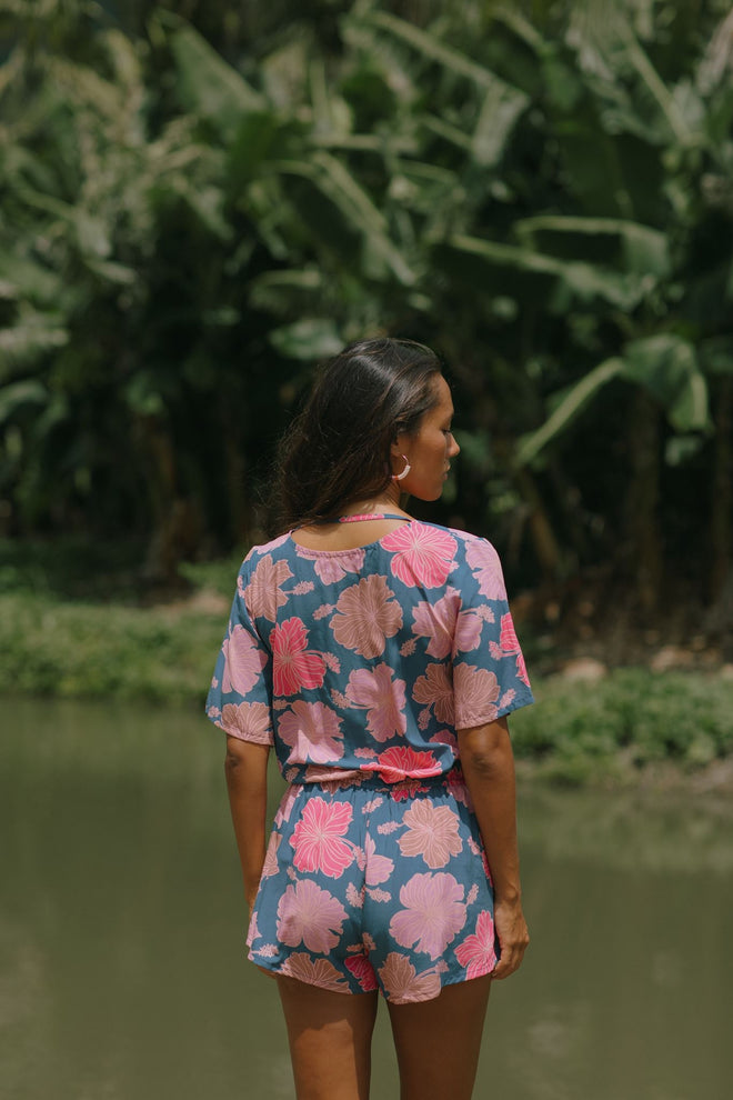 woman with brown hair wearing a navy playsuit with bright pink hibiscus print