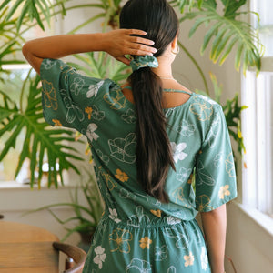 woman wearing lush green scrunchie with puakenikeni print