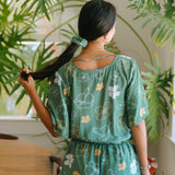 woman wearing lush green scrunchie with puakenikeni print