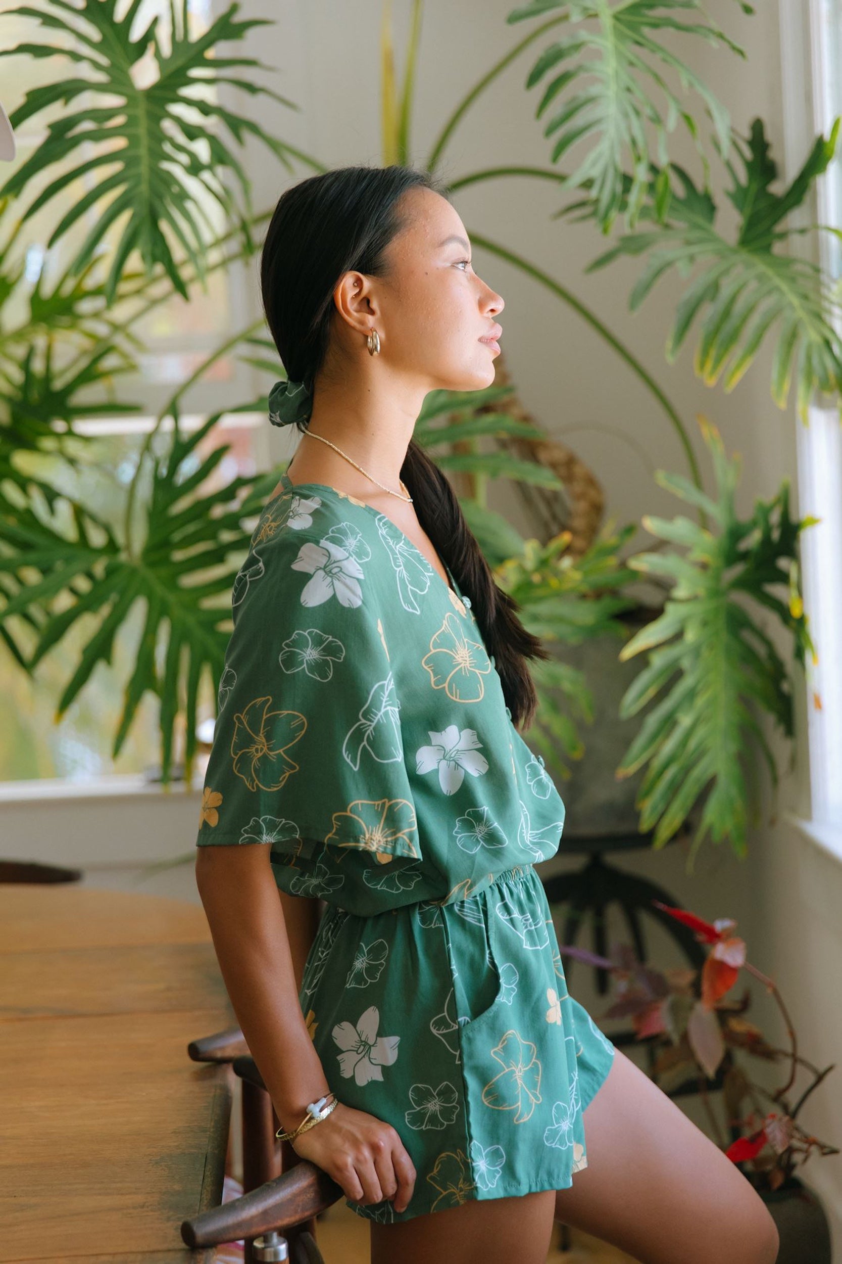 woman with brown hair wearing lush green playsuit with puakenikeni