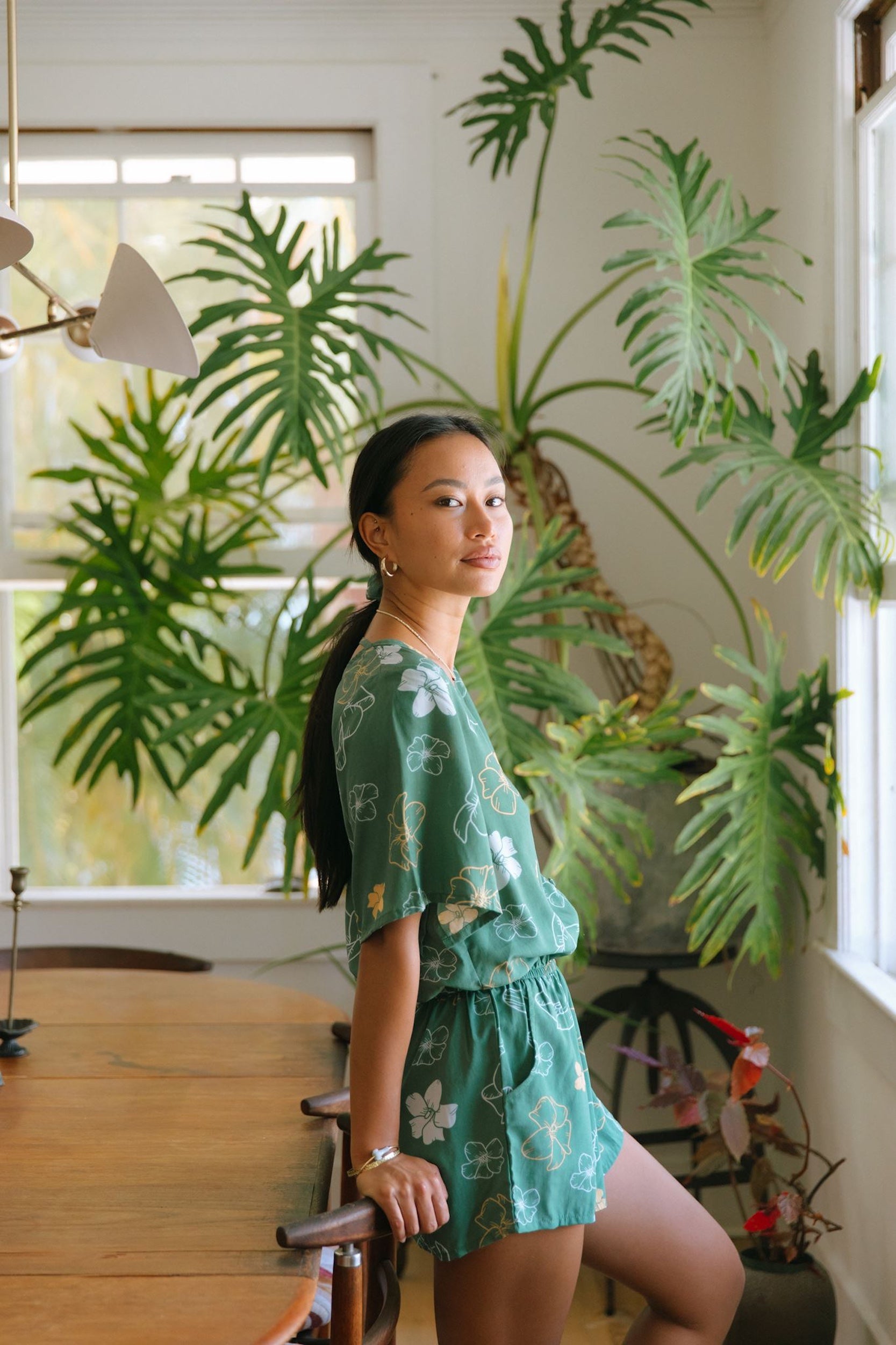 woman with brown hair wearing lush green playsuit with puakenikeni