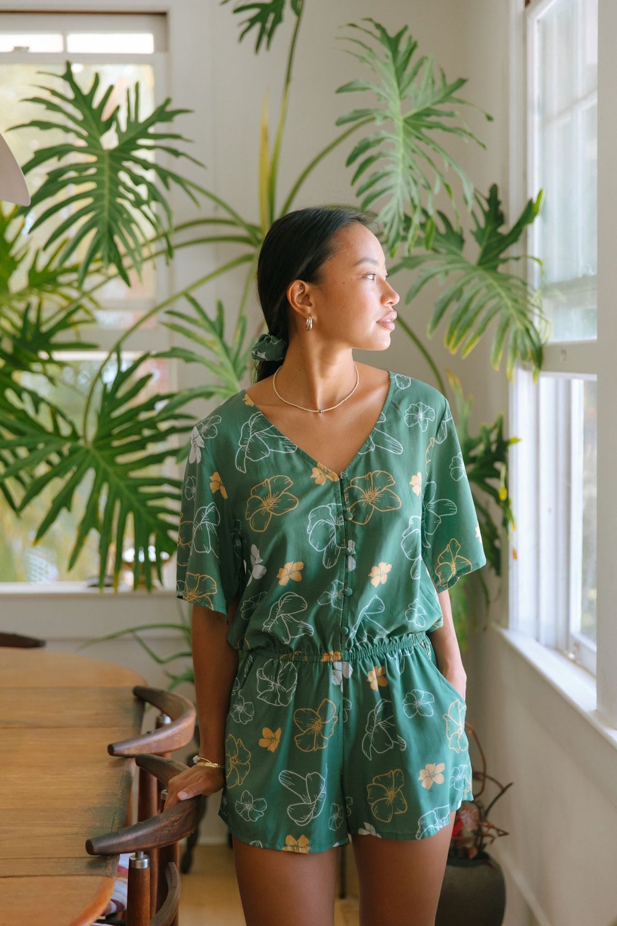 woman with brown hair wearing lush green playsuit with puakenikeni