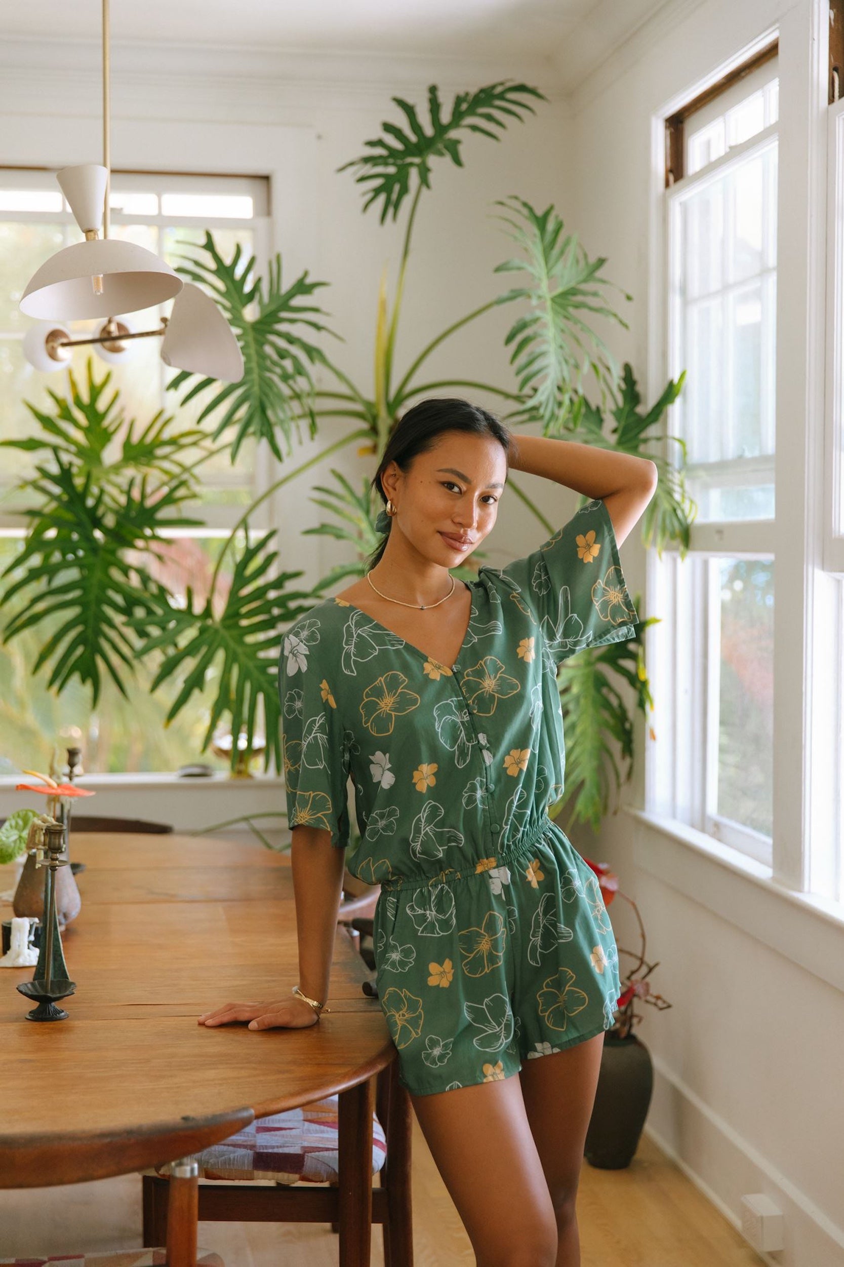 woman with brown hair wearing lush green playsuit with puakenikeni
