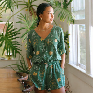 woman with brown hair wearing lush green playsuit with puakenikeni