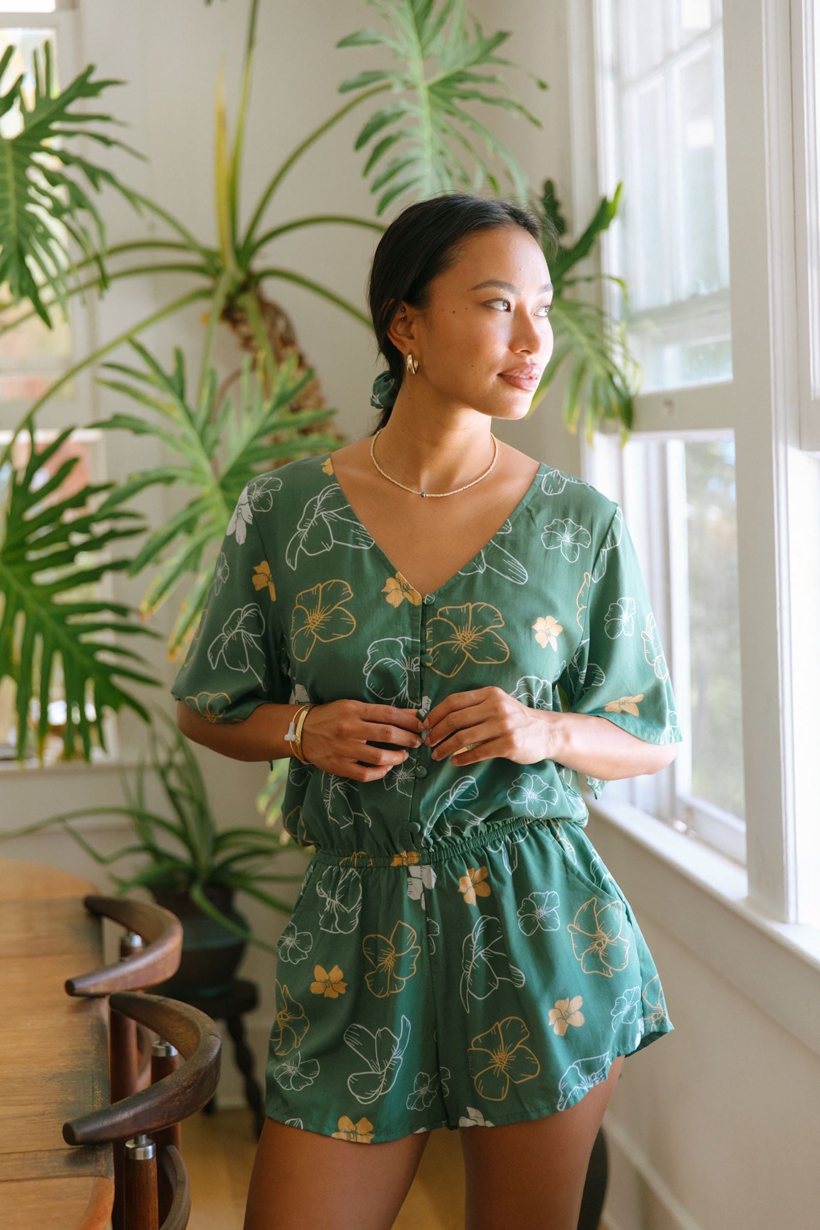 woman with brown hair wearing lush green playsuit with puakenikeni