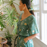 woman with brown hair wearing lush green playsuit with puakenikeni