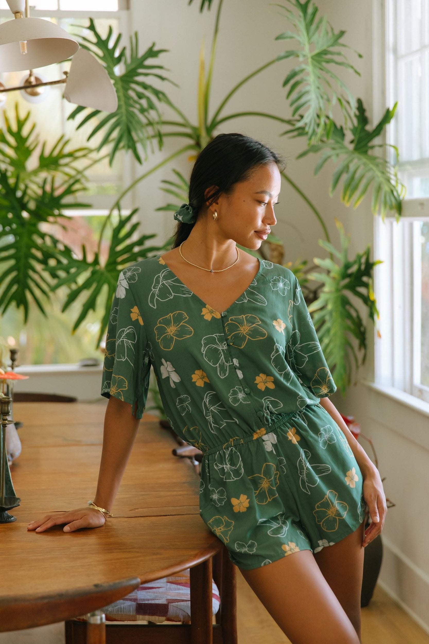 woman with brown hair wearing lush green playsuit with puakenikeni
