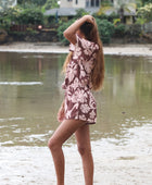 Woman with brown hair wearing a flowy button up playsuit in blush and brown hibiscus print.