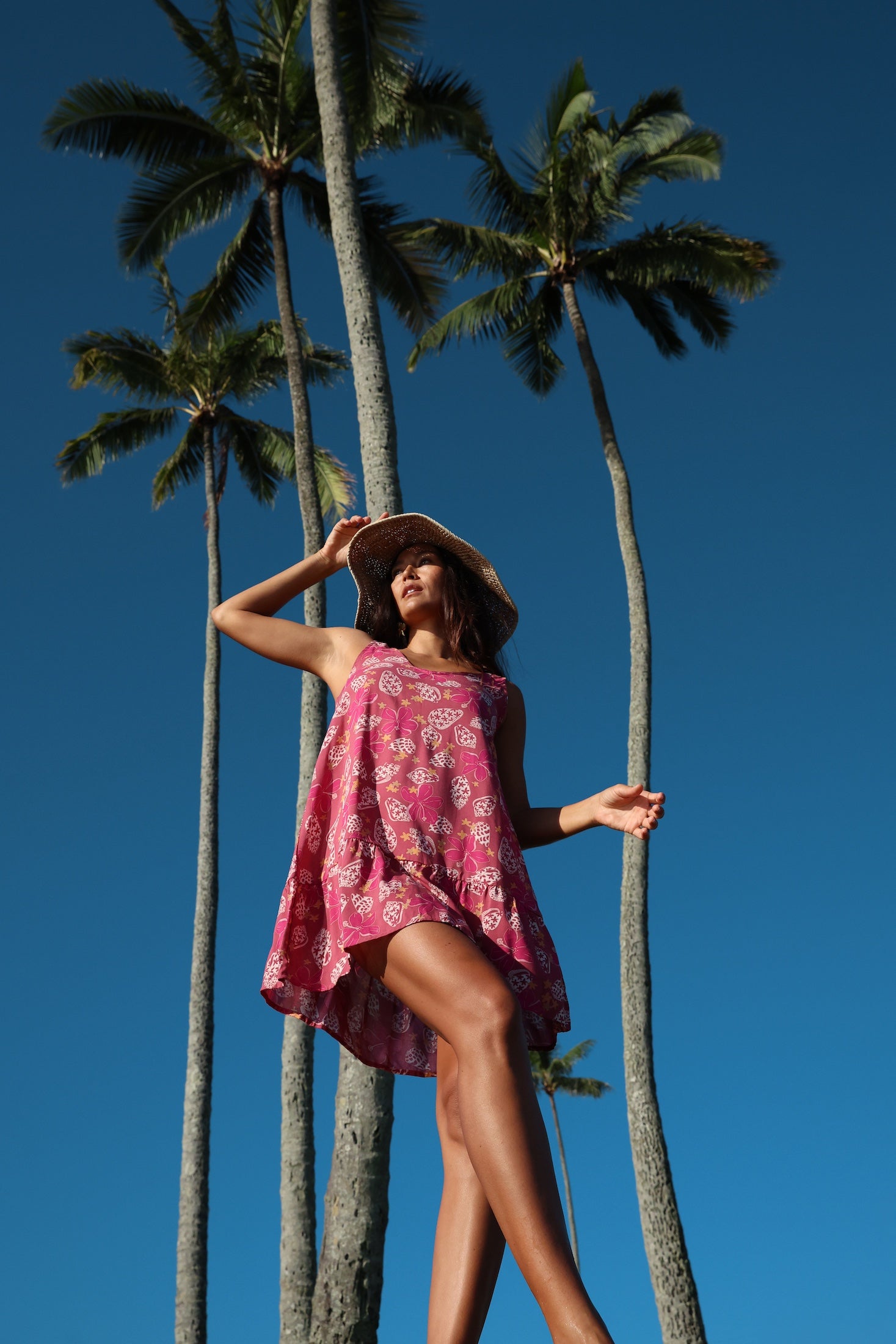 women with brown hair wearing a mini dress with shells and pua print in pink