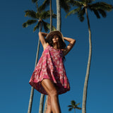 women with brown hair wearing a mini dress with shells and pua print in pink