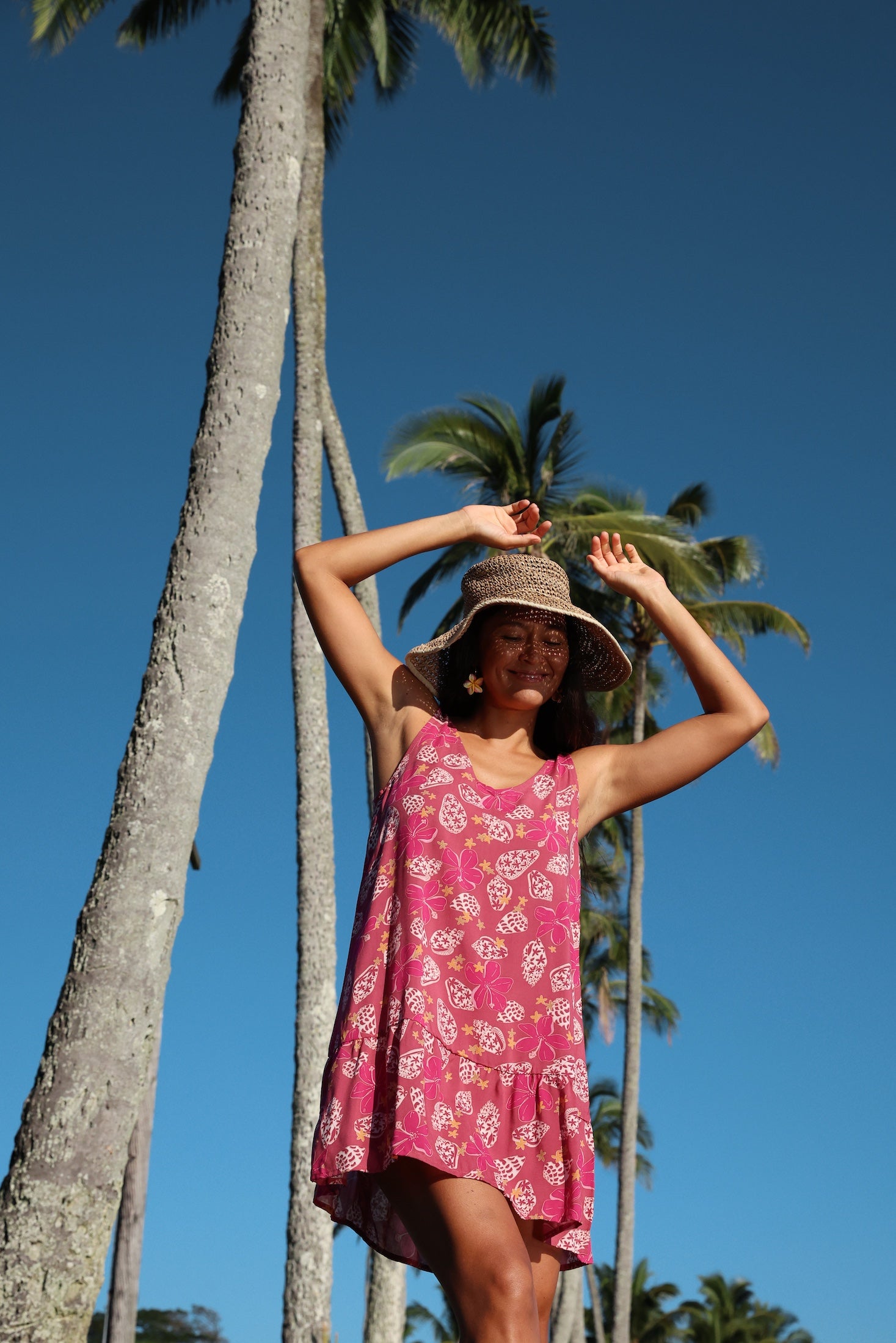 women with brown hair wearing a mini dress with shells and pua print in pink
